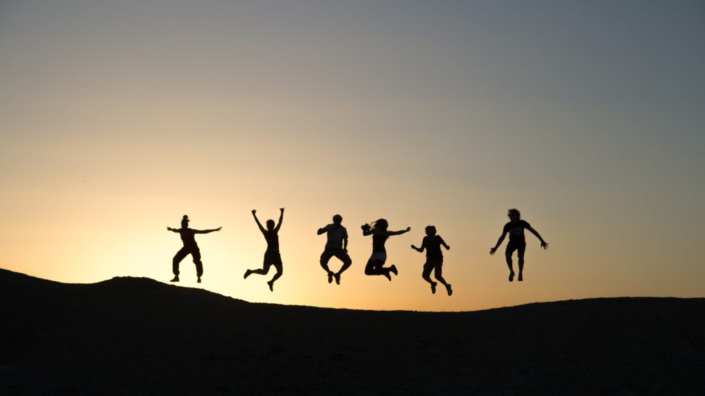 Amigos pulando juntos no pôr do Sol