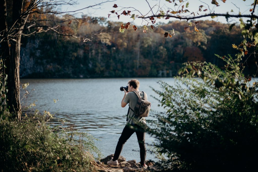 Homem tirando foto próximo a um lago